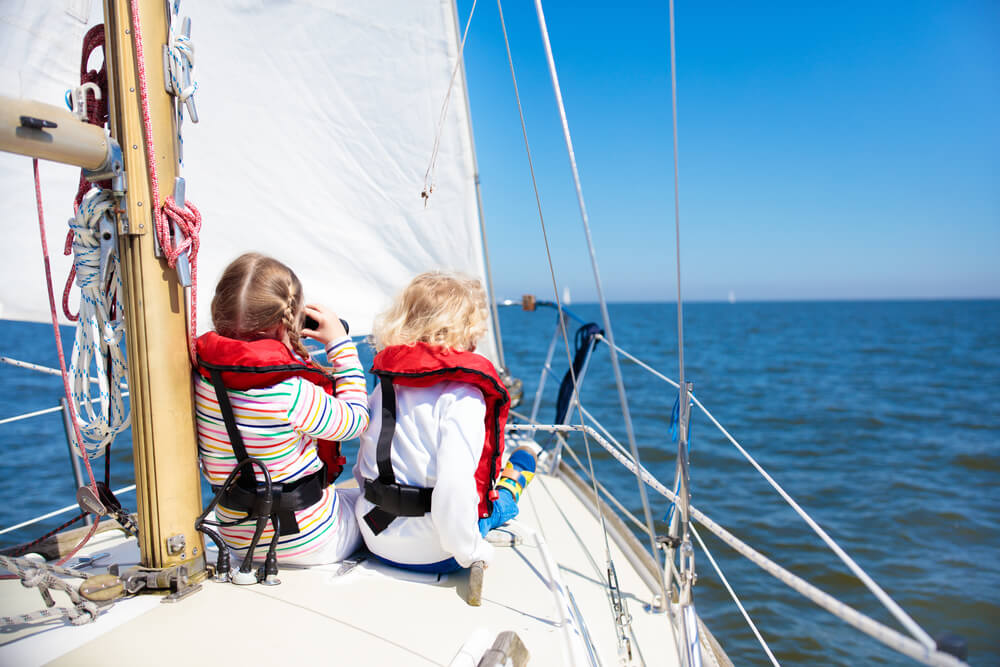 Kinder mit Sicherheitswesten auf einem Segelboot