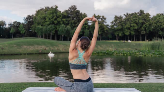 Junge Frau macht Yoga am See